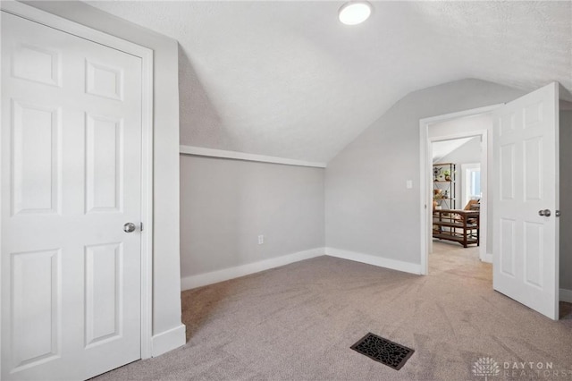 bonus room featuring a textured ceiling, light carpet, and lofted ceiling