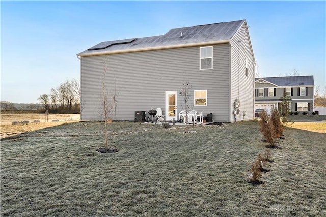 rear view of house with central AC unit and a lawn