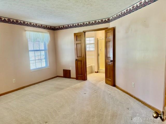 empty room with a textured ceiling and light colored carpet