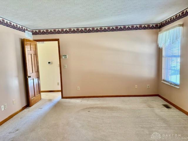 carpeted empty room featuring a textured ceiling