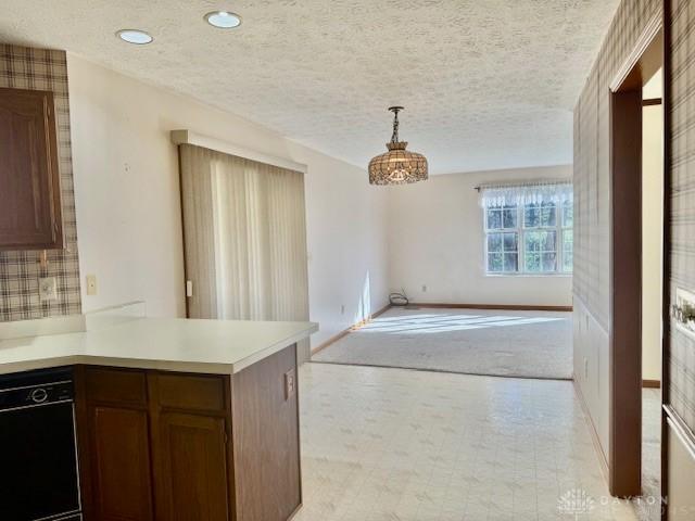 kitchen featuring dishwasher, pendant lighting, a textured ceiling, and light carpet