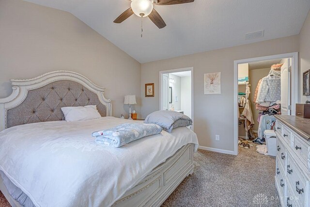 carpeted bedroom featuring ceiling fan, lofted ceiling, and ensuite bath