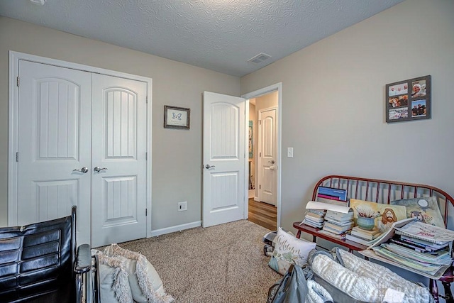 bedroom with carpet floors, a textured ceiling, and a closet