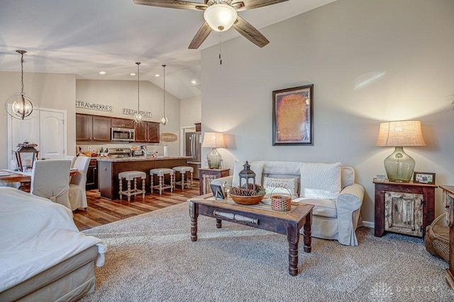 living room with ceiling fan with notable chandelier and high vaulted ceiling