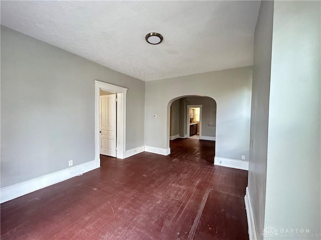 spare room with a textured ceiling and dark wood-type flooring