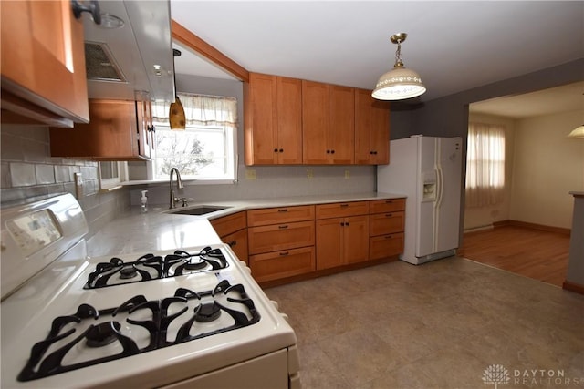 kitchen featuring sink, hanging light fixtures, white appliances, decorative backsplash, and light wood-type flooring