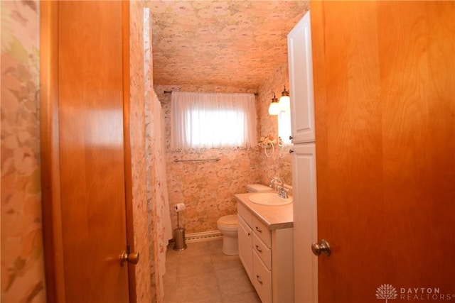 bathroom with toilet, vanity, and tile patterned floors