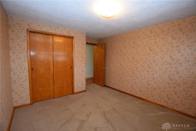 unfurnished bedroom featuring light carpet and a closet