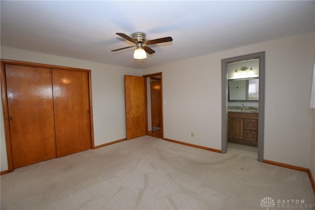 unfurnished bedroom featuring connected bathroom, ceiling fan, sink, light carpet, and a closet