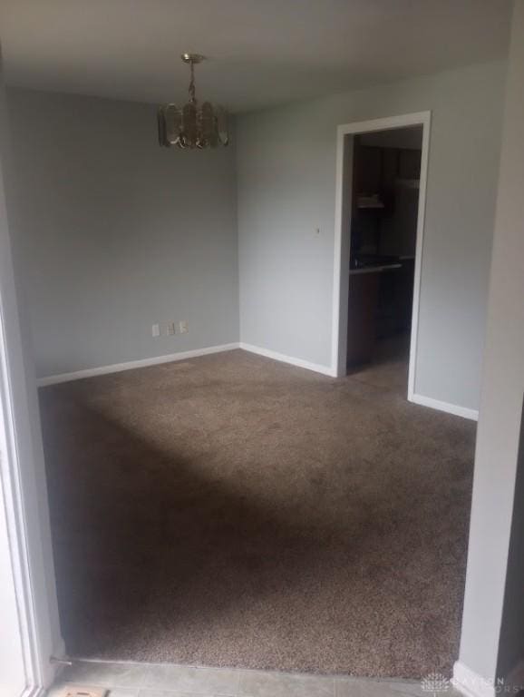 carpeted spare room featuring a notable chandelier