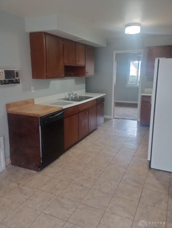 kitchen with dark brown cabinets, white refrigerator, sink, and black dishwasher