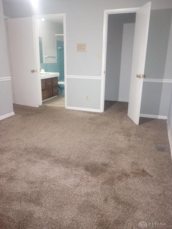 unfurnished bedroom featuring carpet flooring and connected bathroom