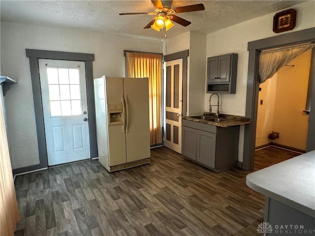 kitchen featuring gray cabinets, white refrigerator with ice dispenser, sink, and dark wood-type flooring