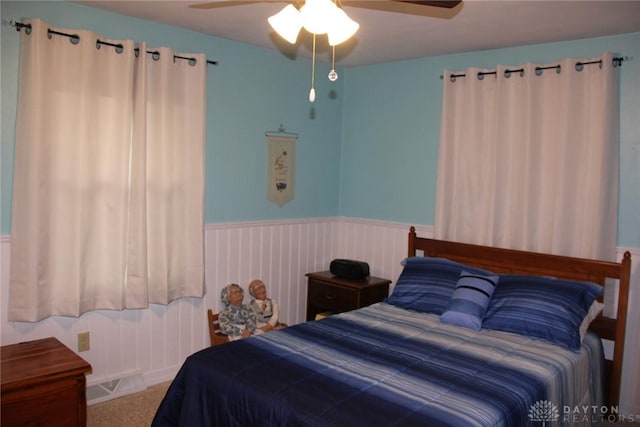 bedroom featuring carpet flooring, wainscoting, and ceiling fan