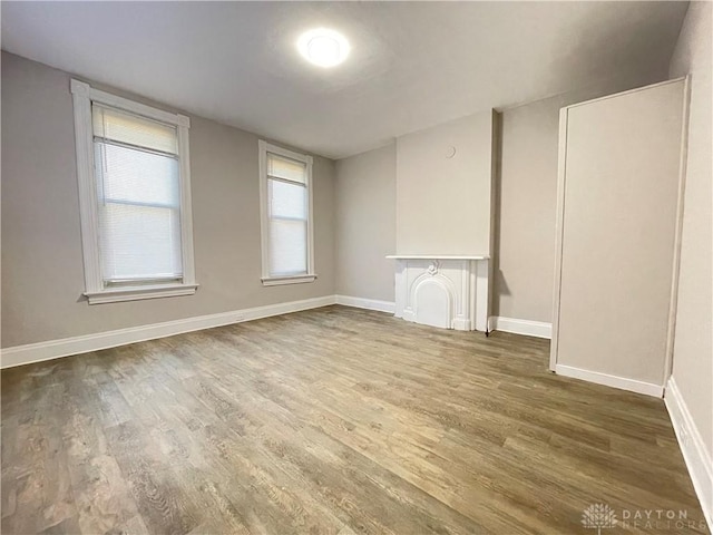 unfurnished room with baseboards, wood finished floors, and a fireplace