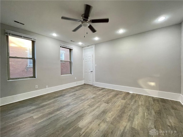 empty room with visible vents, recessed lighting, dark wood-type flooring, and baseboards