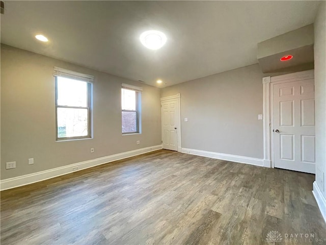 empty room featuring recessed lighting, baseboards, and dark wood finished floors