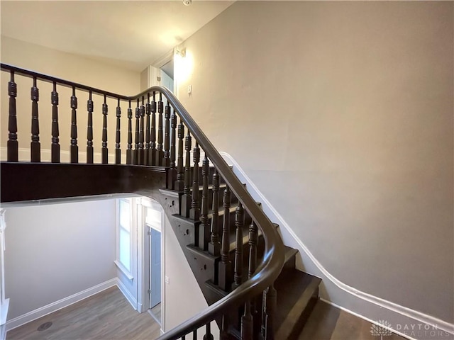 staircase featuring baseboards and wood finished floors