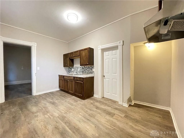 kitchen featuring light countertops, dark brown cabinets, baseboards, and light wood-type flooring