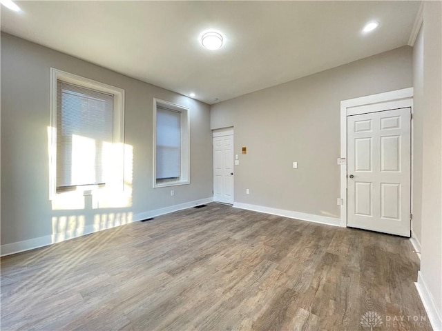 spare room featuring visible vents, baseboards, and wood finished floors