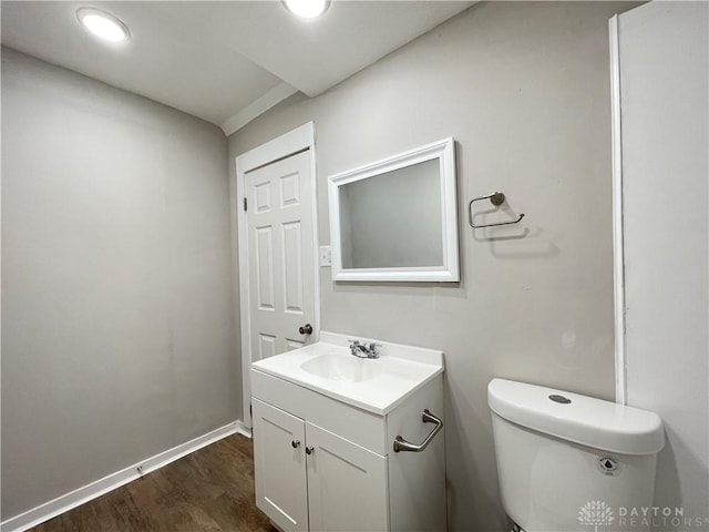 half bathroom featuring toilet, wood finished floors, recessed lighting, baseboards, and vanity