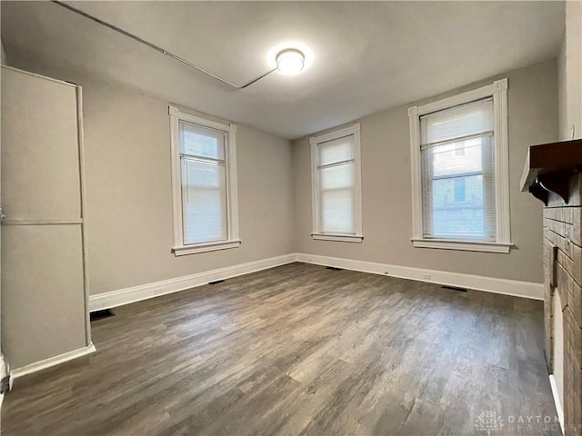 interior space with dark wood finished floors, visible vents, a fireplace, and baseboards