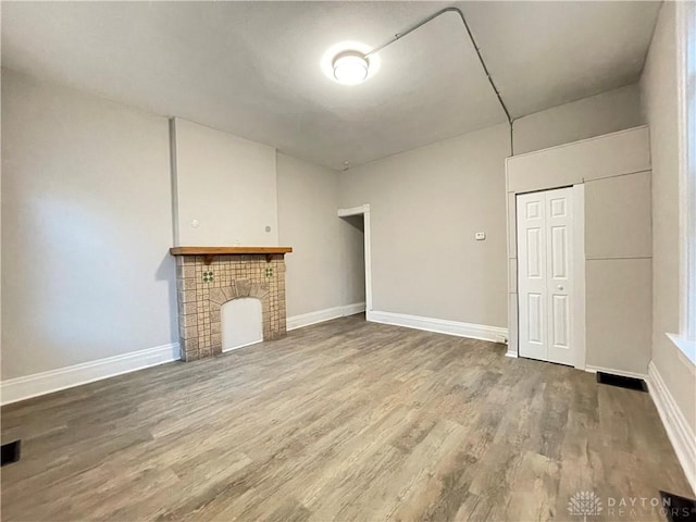 unfurnished living room with baseboards, wood finished floors, and a fireplace