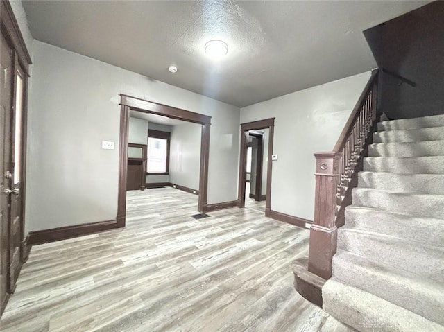 foyer entrance with a textured ceiling and light hardwood / wood-style floors