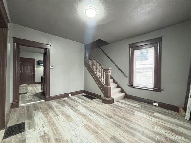 spare room with a textured ceiling and light wood-type flooring