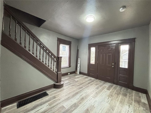 entryway with a textured ceiling, light hardwood / wood-style floors, and a wealth of natural light