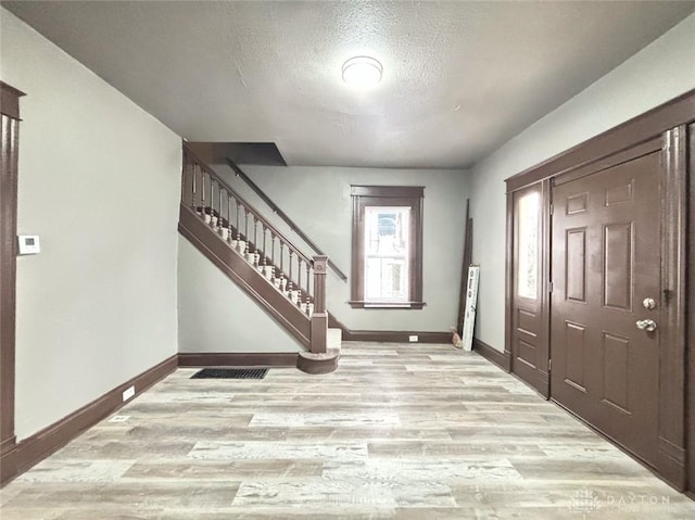 foyer entrance featuring light wood-type flooring and a textured ceiling