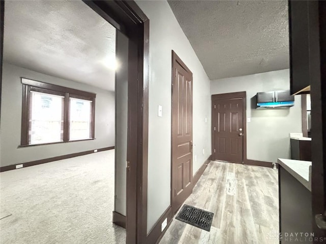 hall with light hardwood / wood-style floors and a textured ceiling