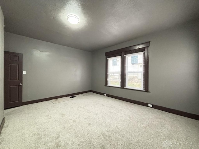 carpeted empty room featuring a textured ceiling