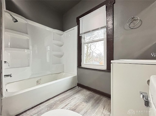 bathroom featuring hardwood / wood-style flooring, toilet, and bathing tub / shower combination