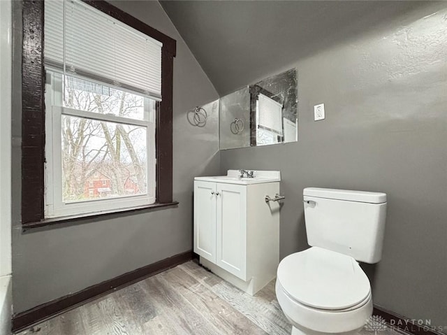 bathroom featuring hardwood / wood-style flooring, vanity, toilet, and vaulted ceiling