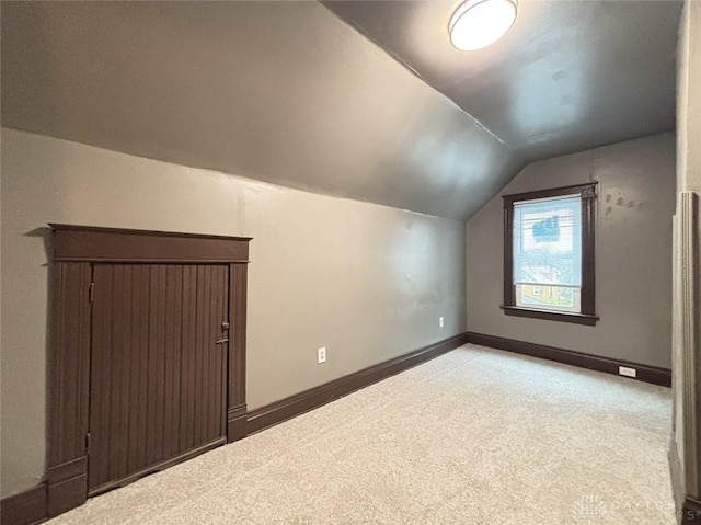 additional living space with light colored carpet and vaulted ceiling