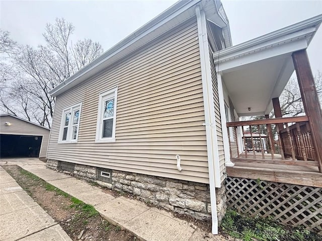 view of side of home featuring a garage, an outdoor structure, and a wooden deck