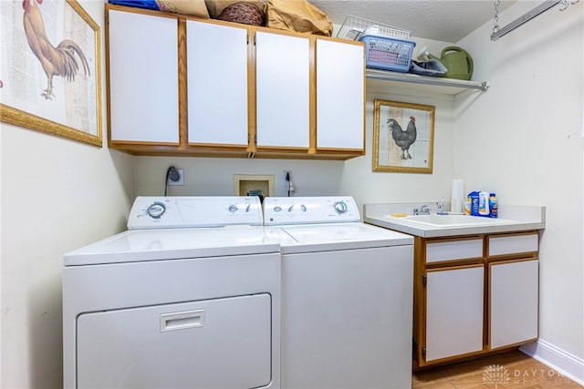 laundry room featuring cabinets, a textured ceiling, washer and clothes dryer, and sink