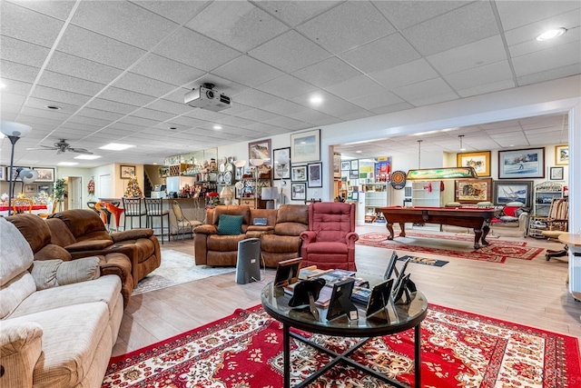 living room featuring light wood-type flooring, a drop ceiling, ceiling fan, and pool table