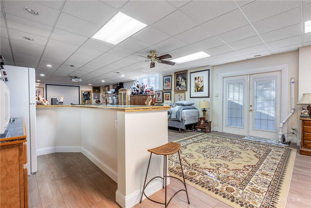 kitchen featuring a paneled ceiling, french doors, ceiling fan, light hardwood / wood-style floors, and kitchen peninsula