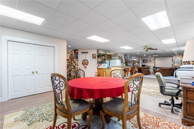 dining space featuring ceiling fan, a drop ceiling, and light hardwood / wood-style flooring