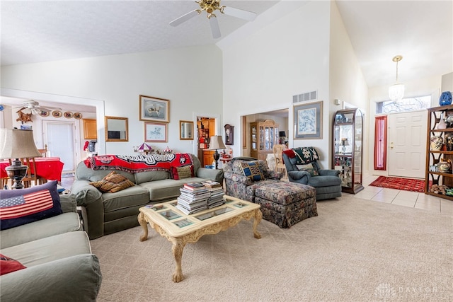 carpeted living room with ceiling fan and high vaulted ceiling