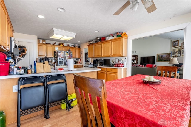 kitchen with stainless steel fridge with ice dispenser, a textured ceiling, and light wood-type flooring