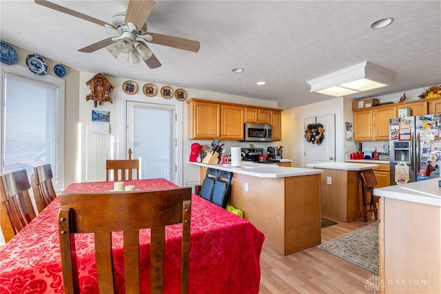 kitchen featuring a center island, a textured ceiling, appliances with stainless steel finishes, and light hardwood / wood-style flooring