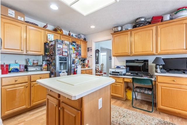 kitchen with stainless steel fridge, light wood-type flooring, a textured ceiling, and a kitchen island