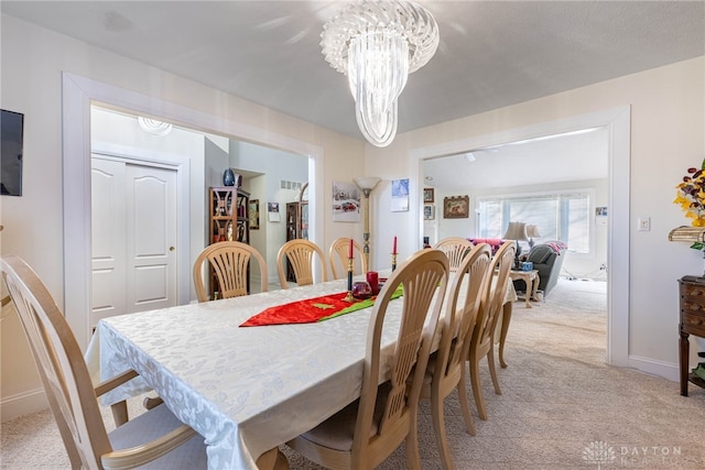 dining area featuring light colored carpet and an inviting chandelier