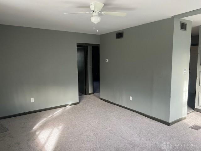 carpeted spare room with ceiling fan