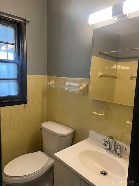 bathroom with vanity, toilet, and tile walls