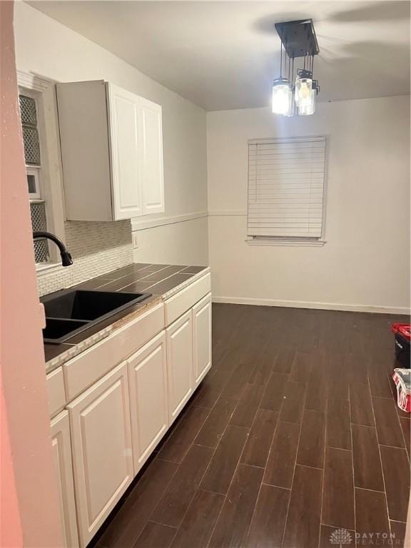 kitchen featuring tile countertops, dark wood-type flooring, white cabinets, sink, and hanging light fixtures