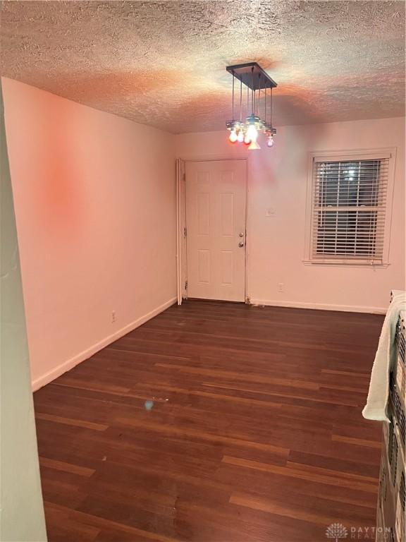 spare room featuring a textured ceiling and dark hardwood / wood-style flooring